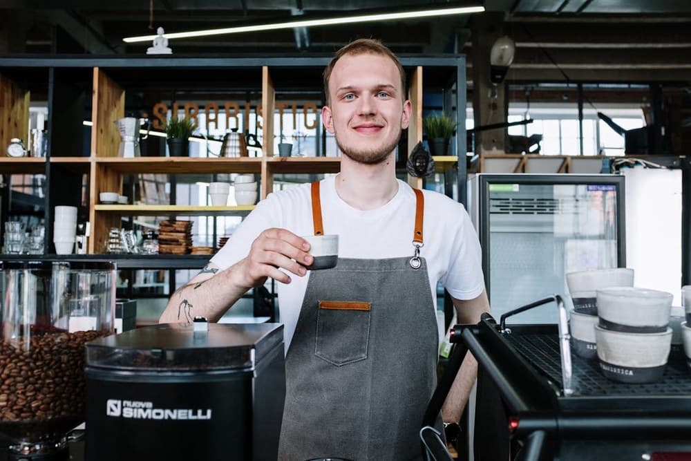 Smiling barista holding a coffee cup in a cafe